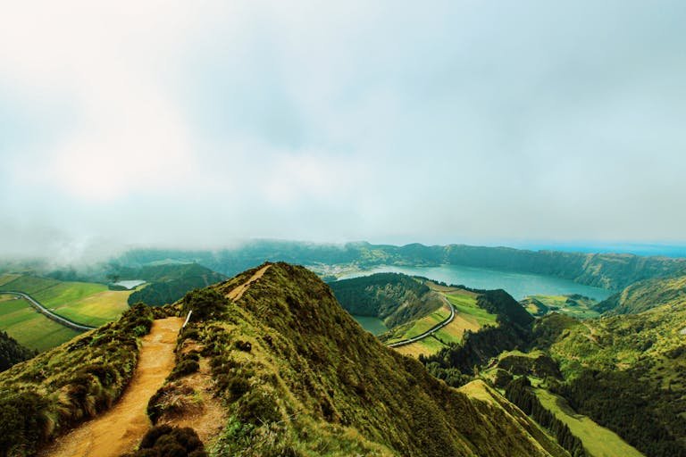Explore the scenic beauty of the Azores with mountains, lush greenery, and a foggy lagoon view.